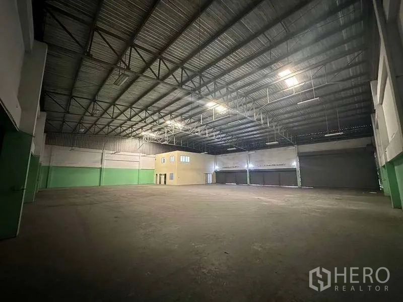 Factory for rent in Nonthaburi - High-clearance warehouse interior featuring several loading shutters and clear span floor.