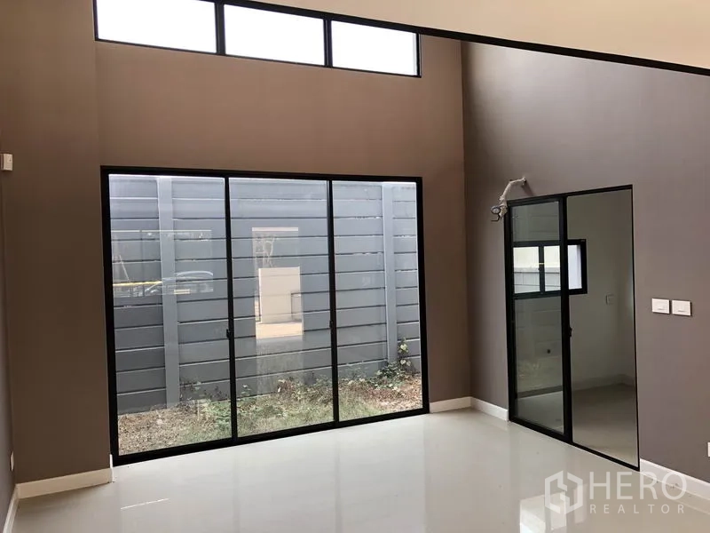 联排别墅 出售在Saphan Sung, Bangkok - 挑高中庭客厅，落地推拉门通向小庭院，采光充足。