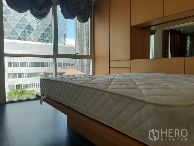 Condominium for rent in Phaya Thai, Bangkok - Bedroom with large windows, city view and built-in wooden wardrobes.