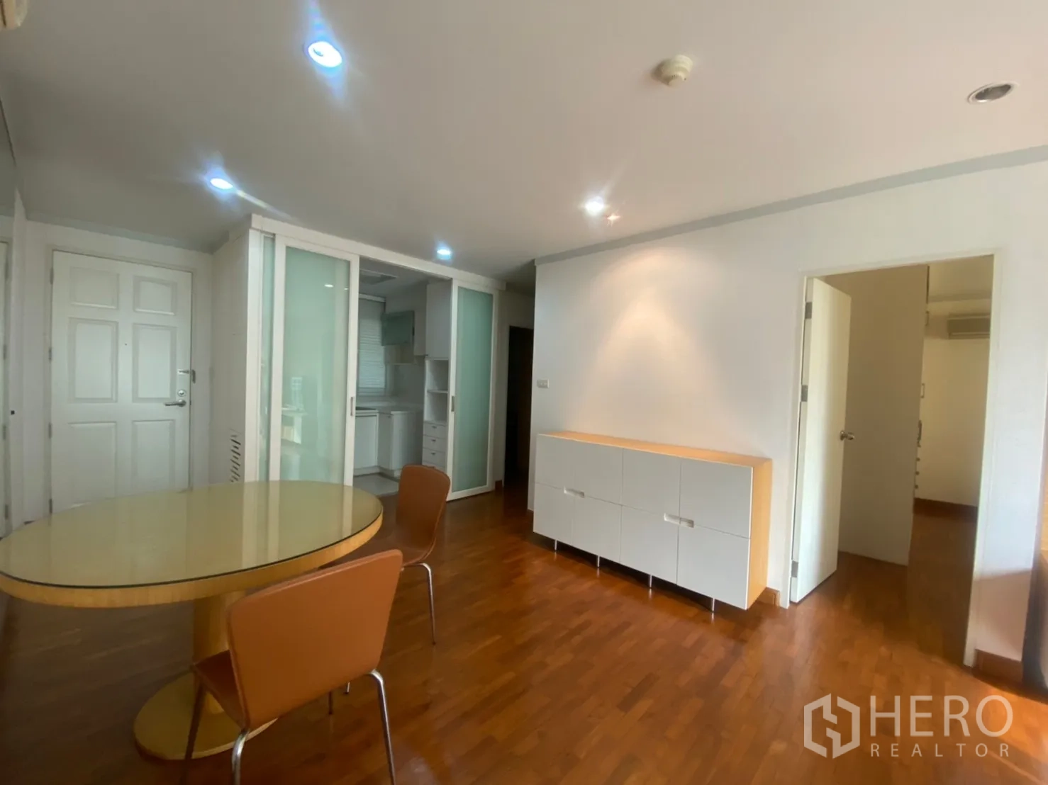 公寓 出租或出售在Sathon, Bangkok - 餐区设圆桌与椅子，旁有磨砂玻璃门通往厨房