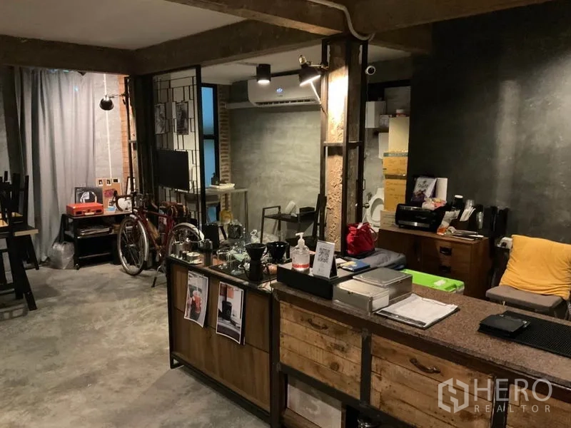 Home Office for rent in Phaya Thai, Bangkok - Open-plan home office with industrial concrete floors, exposed brick pillars, metal partitions, reception counter and split air conditioner.