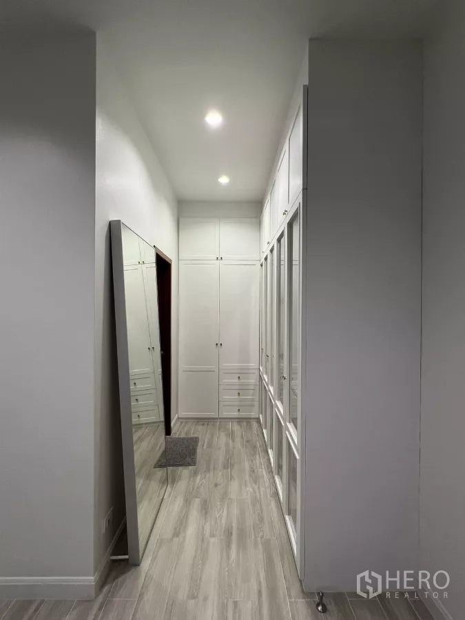 公寓 出租在Bang Kapi, Bangkok - 步入式衣帽间走廊，通顶白色衣柜与全身镜。