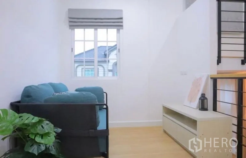 Detached House for rent in Bang Phli, Samut Prakan - Upstairs family area with teal loveseat next to window by staircase.