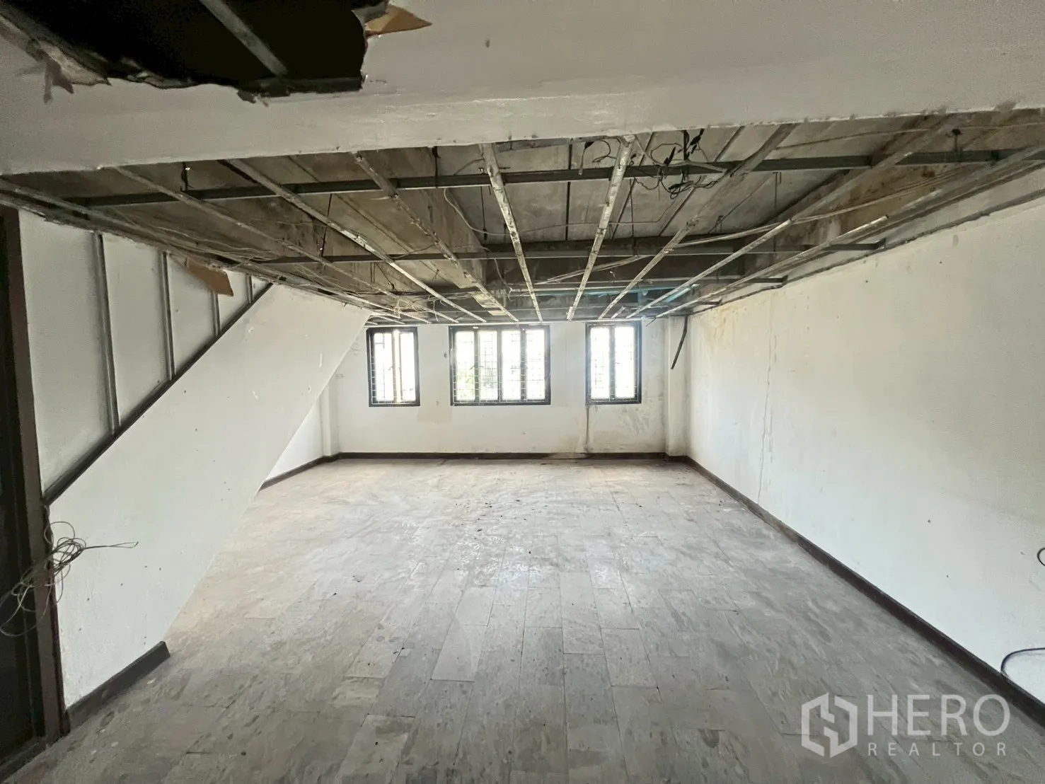 Shophouse for rent in Phra Khanong, Bangkok - Large open-plan floor with exposed ceiling grid and three front windows.