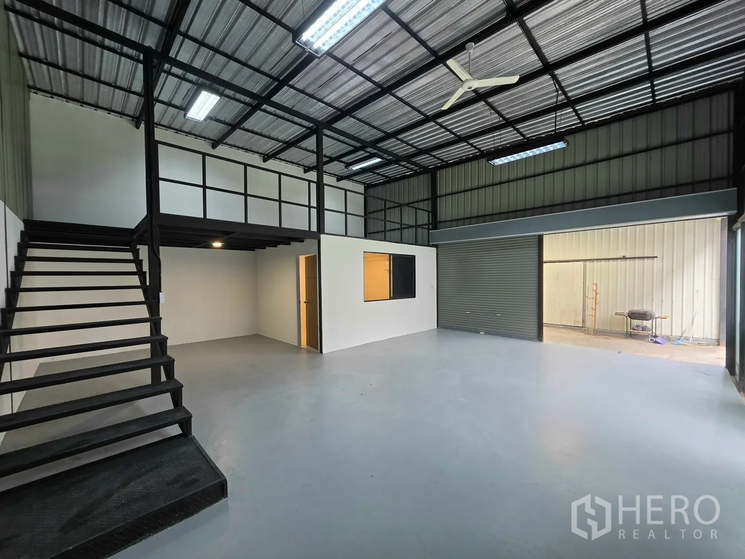 โกดัง for rent in Suan Luang, Bangkok - พื้นที่โกดังกว้างพร้อมชั้นลอย บันได และประตูม้วนเปิดเชื่อมภายนอก.