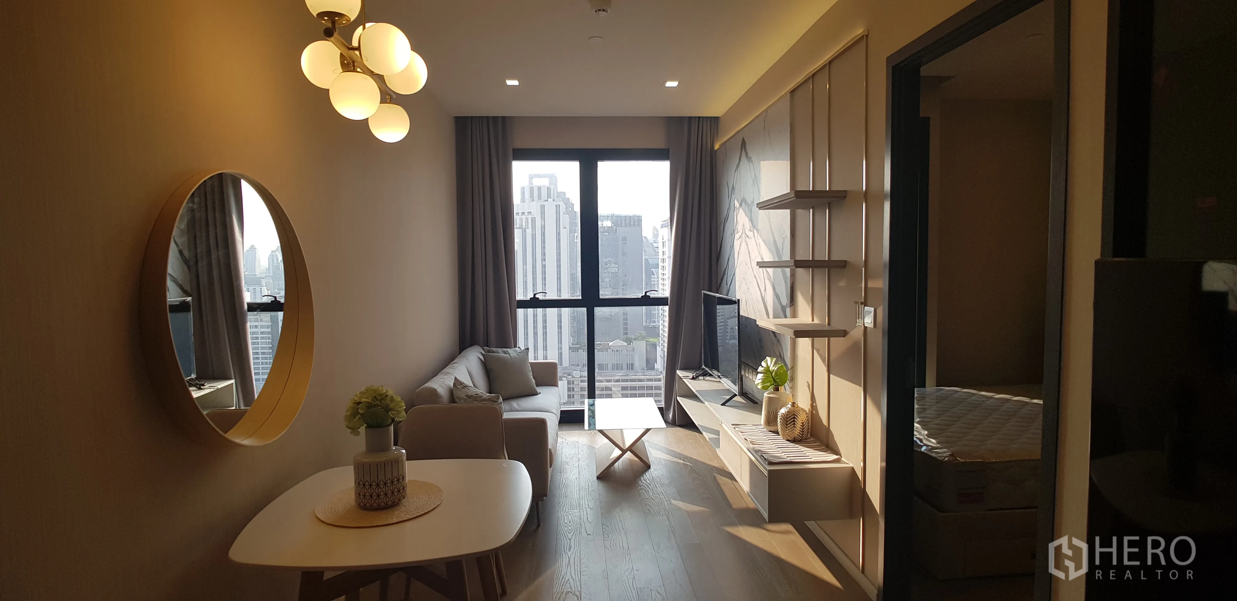 คอนโด for rent in Watthana, Bangkok - ห้องนั่งเล่นสว่าง โซฟา ผนังทีวี และหน้าต่างสูงเต็มบาน มองเห็นวิวสกายไลน์กรุงเทพฯ