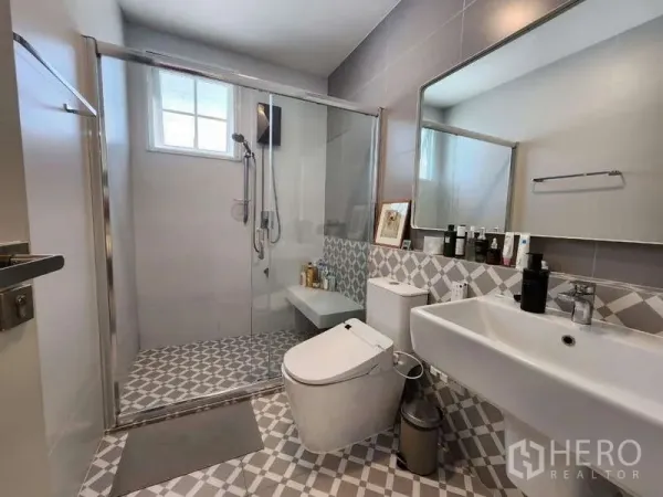 Detached House for rent or sale in Bang Phli, Samut Prakan - Contemporary bathroom with glass-enclosed shower, patterned floor tiles and wide vanity.