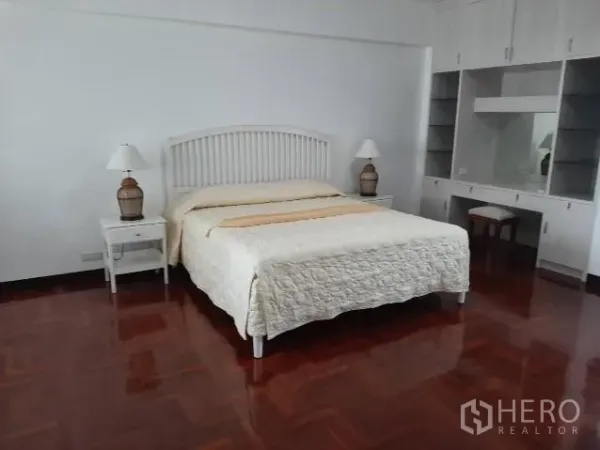 公寓 出租在Khlong Toei, Bangkok - 宽敞主卧，白色床头配床头灯，内置衣柜与梳妆台，实木地板光亮整洁。
