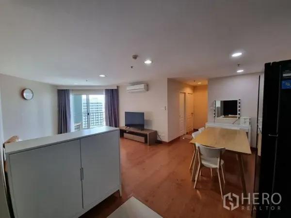 公寓 出租在Huai Khwang, Bangkok - 客餐厅一体，通向阳台的玻璃门、电视柜与窗帘。