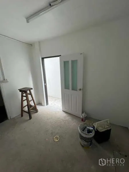 Shophouse for rent in Watthana, Bangkok - Compact room with a white door featuring glass panels and unfinished floor.