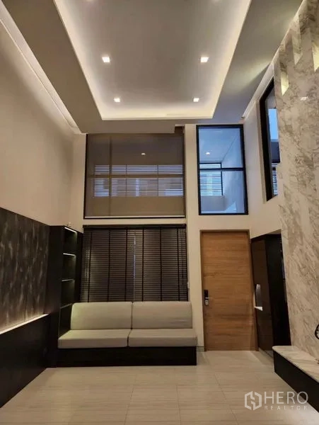 Townhouse for sale in Yan Nawa, Bangkok - Double-height living area with recessed lighting, sofa seating and large blinds in a modern Bangkok townhouse.