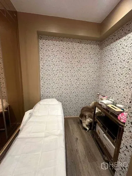 Retail Space for rent in Khlong Toei, Bangkok - Compact treatment room featuring a massage bed, terrazzo accent wall, wood flooring, and a storage trolley.
