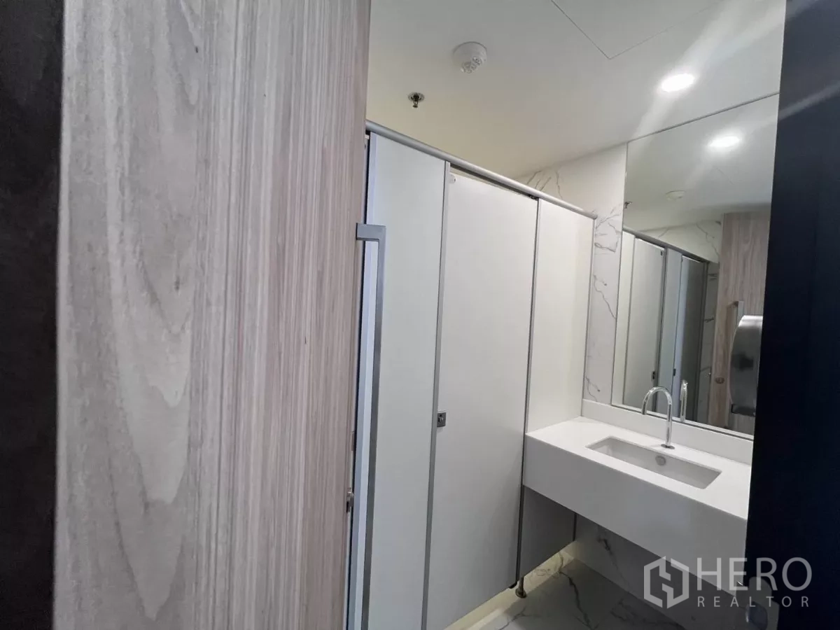 Office Space for rent in Din Daeng, Bangkok - Modern restroom with white stall doors, large mirror and integrated sink.