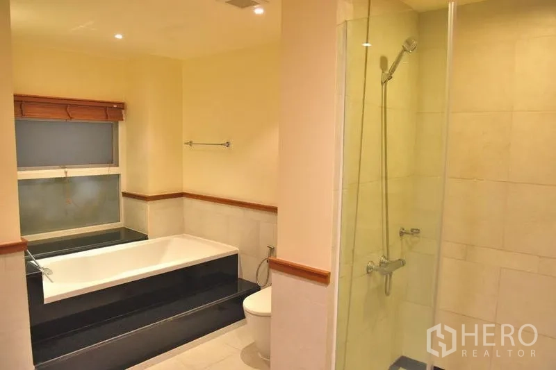 Apartment for rent in Sathon, Bangkok - Bathroom featuring a separate bathtub and glass shower enclosure.