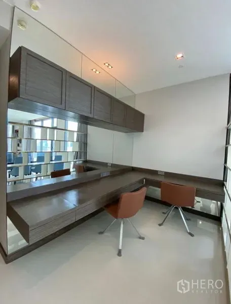 Condominium for rent in Khlong Toei, Bangkok - Bright study or vanity room with wall-to-wall mirrors, floating desk and two modern chairs.