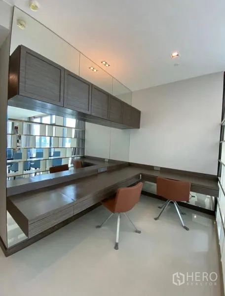Condominium for rent in Khlong Toei, Bangkok - Bright study or vanity room with wall-to-wall mirrors, floating desk and two modern chairs.