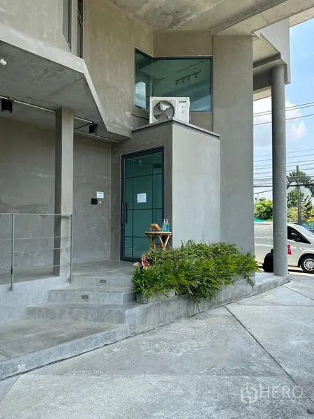 带办公室的家 出租或出售在Prawet, Bangkok - 主入口设玻璃门、台阶与绿化，极简混凝土风格。