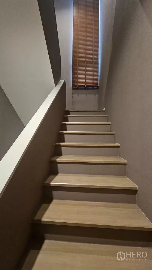 Townhouse for rent in Saphan Sung, Bangkok - Wood staircase with a tall window and blinds bringing natural light.