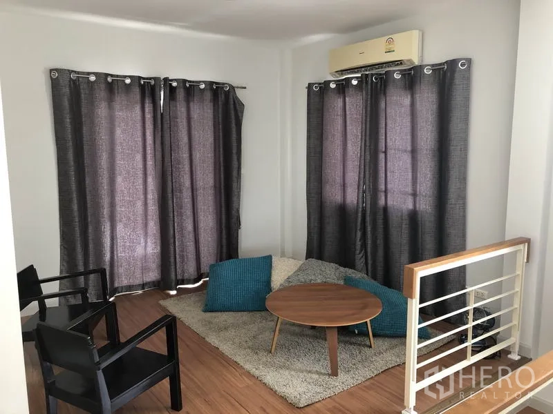 Detached House for rent or sale in Bang Kapi, Bangkok - Upstairs family lounge with rug, chairs and air conditioning beside the staircase landing.