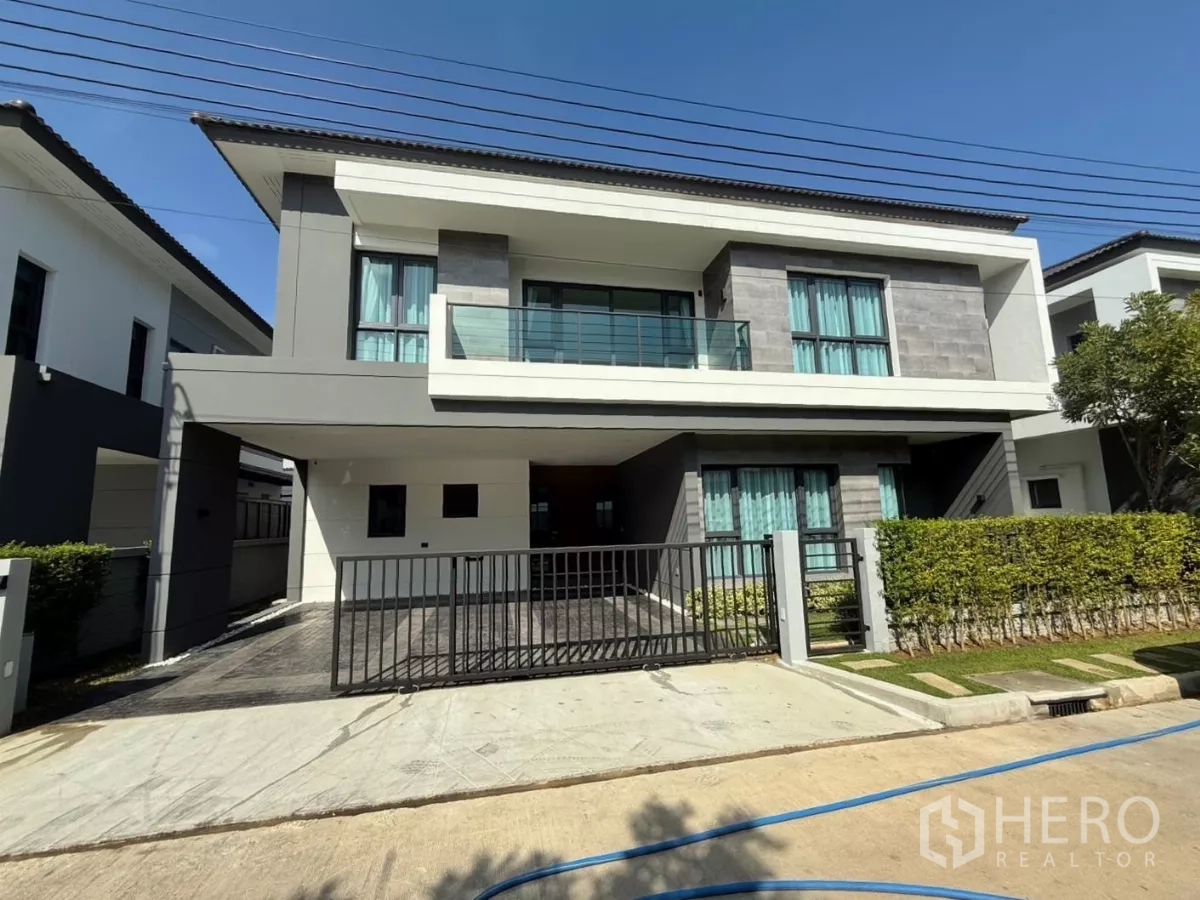 独立式住宅 出租在Bang Phli, Samut Prakan - 带金属大门车道与阳台的两层独栋别墅外观。