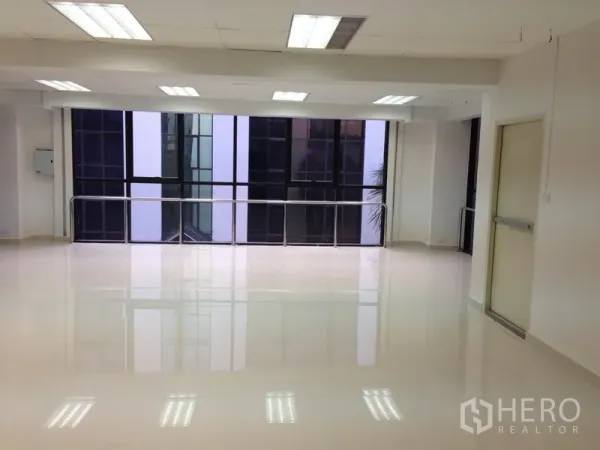 Office Space for rent in Bang Kapi, Bangkok - Bright open-plan office interior in Bang Kapi with large windows, glossy tile floor, ceiling lights and a side fire-exit door.