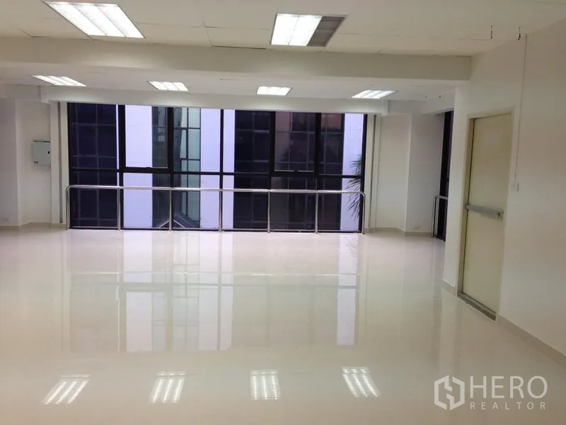 Office Space for rent in Bang Kapi, Bangkok - Bright open-plan office interior in Bang Kapi with large windows, glossy tile floor, ceiling lights and a side fire-exit door.