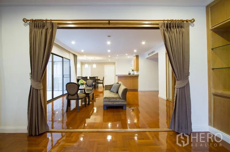 Apartment for rent in Watthana, Bangkok - Formal living space with curtain partition opening to dining area and breakfast-bar kitchen.