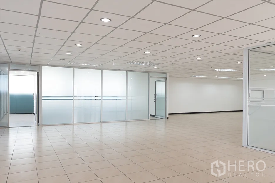 Office Space for rent in Din Daeng, Bangkok - Open‑plan office interior with beige tile flooring, recessed lighting, and frosted glass partitions creating meeting rooms.