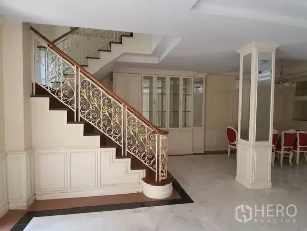 Townhouse for rent in Huai Khwang, Bangkok - Elegant staircase with wrought-iron balustrade and built-in display cabinets.