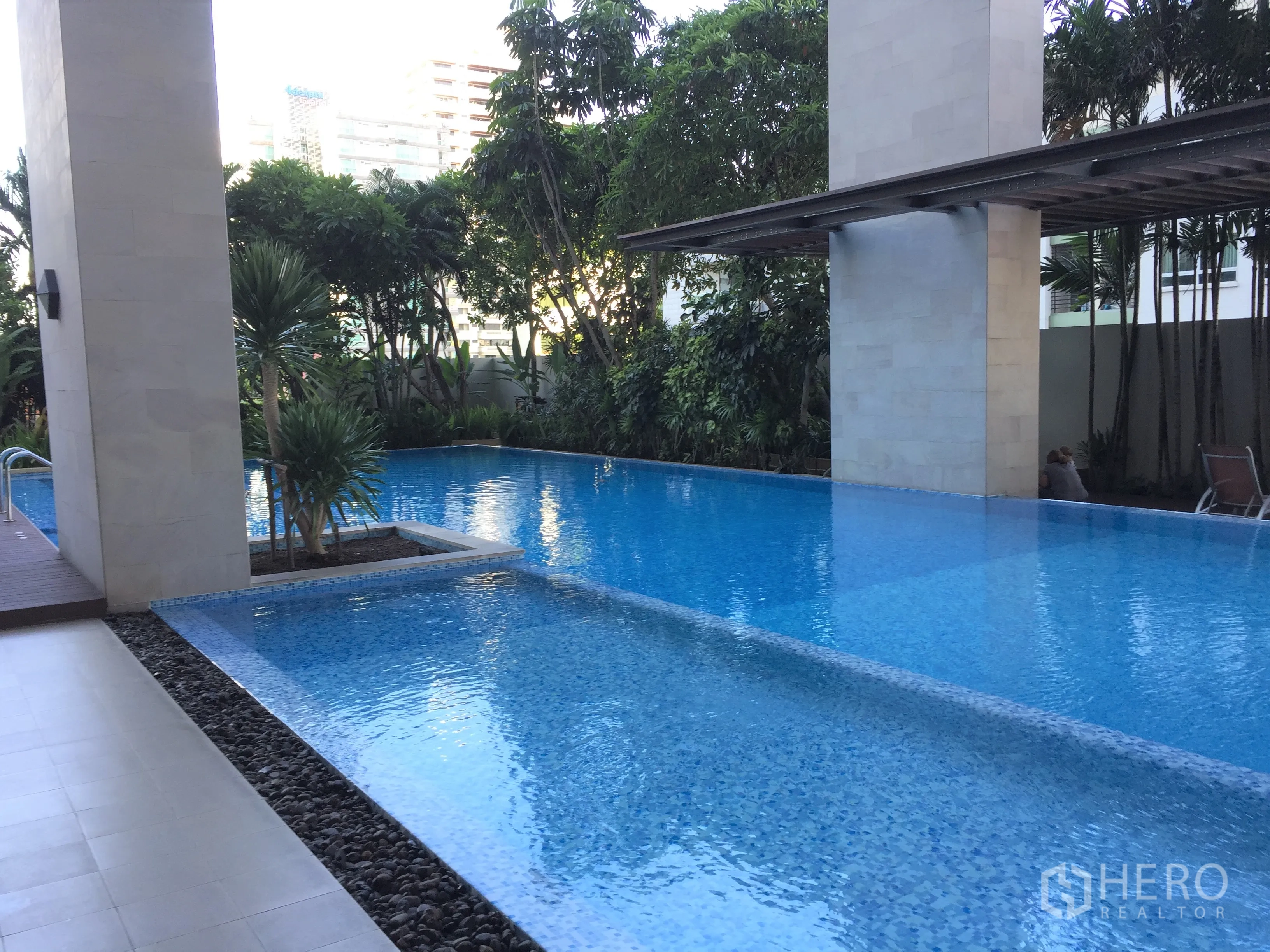 公寓 出租在Watthana, Bangkok - 公寓热带风情泳池，环绕绿植并设有遮荫休憩区。