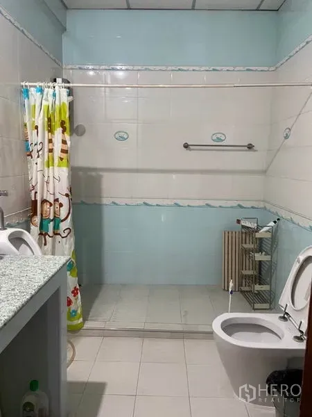 联排别墅 出租在Khlong Toei, Bangkok - 瓷砖浴室，设步入式淋浴区、洗手台与坐便器，带浴帘。