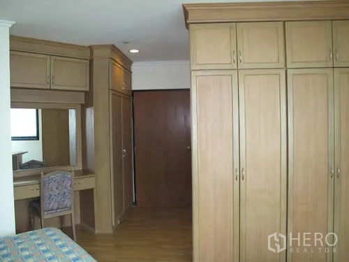 Condominium for rent in Sathon, Bangkok - Bedroom with built-in wardrobes, dressing table and wood flooring.