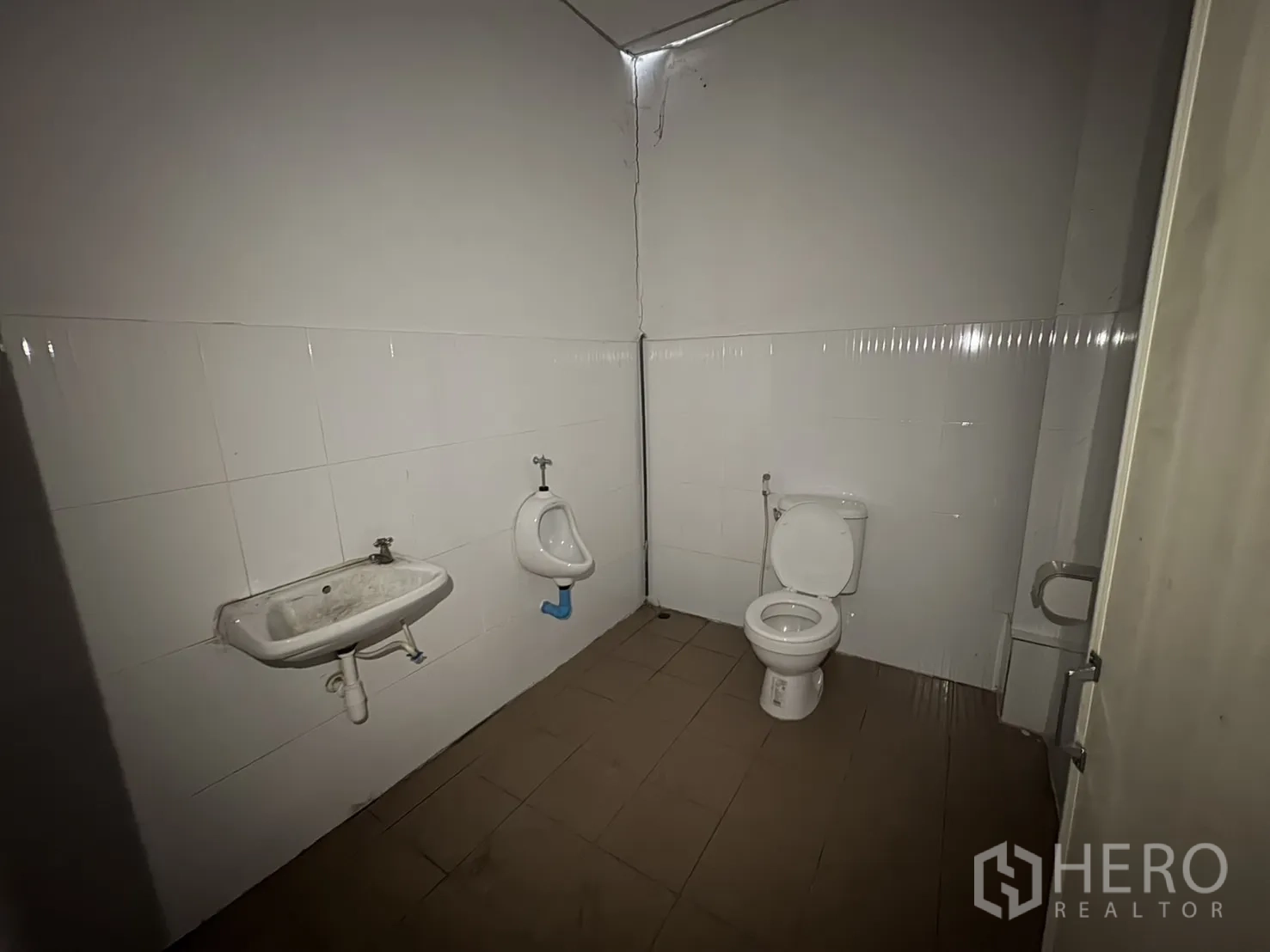 Warehouse for rent in Mueang Samut Prakan, Samut Prakan - Clean tiled restroom with toilet, urinal and wall‑mounted sink inside the facility.