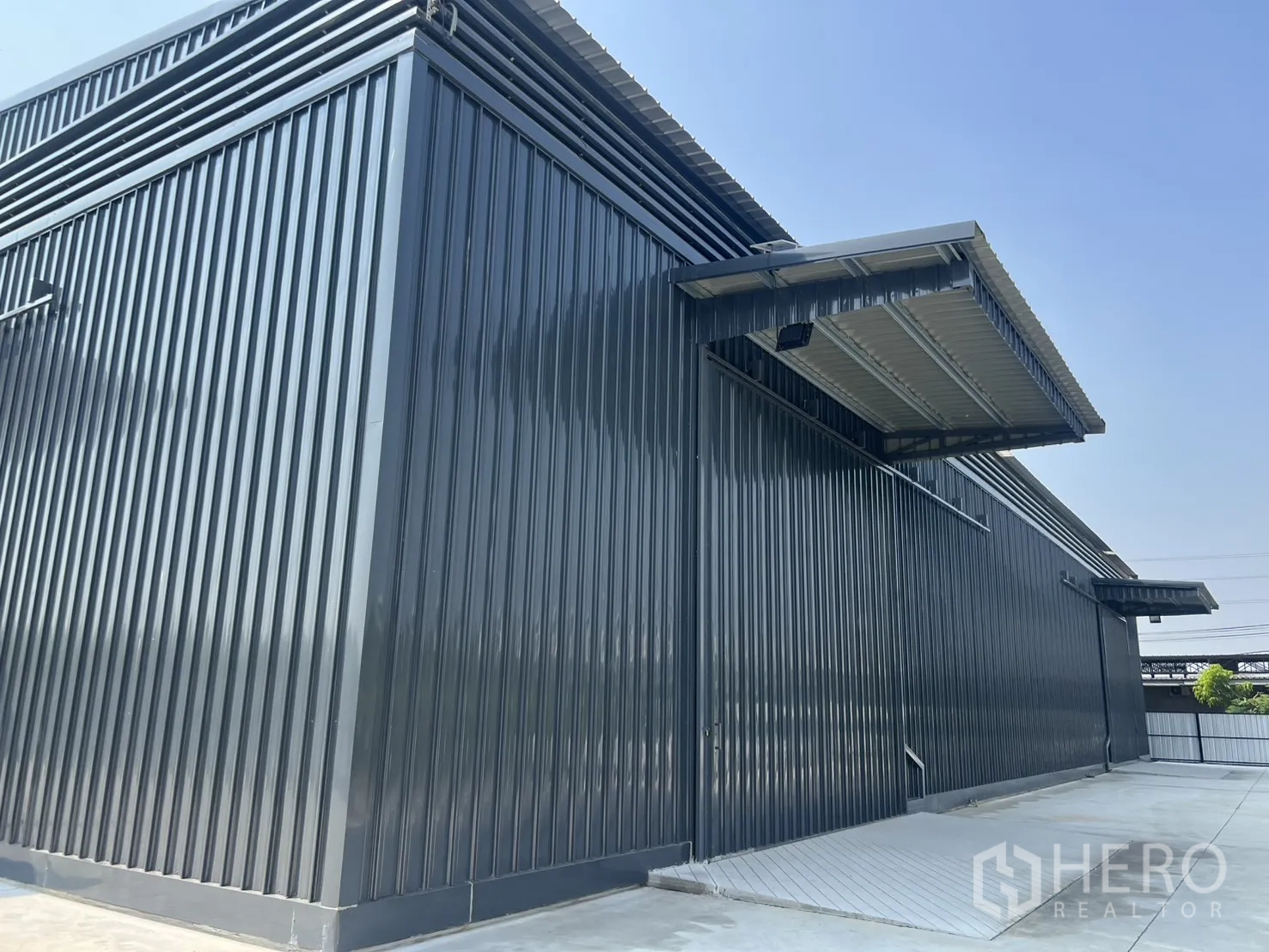 货栈 出租在Lat Krabang, Bangkok - 仓库转角视图，金属波纹墙面，带装卸坡道与遮蔽月台。