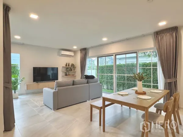 Detached House for rent in Bang Phli, Samut Prakan - Spacious living area with TV, floating shelves and wraparound windows overlooking the lawn.
