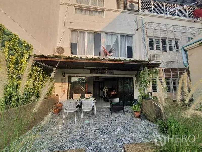 Townhouse for rent or sale in Bang Kho Laem, Bangkok - Rear exterior of multi-storey townhouse with tiled patio, awning and planter walls.