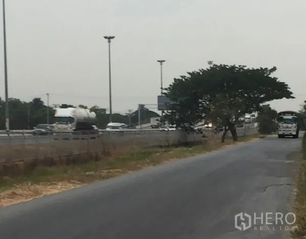 Warehouse for rent in Khlong Luang, Pathum Thani - Access road connecting to a nearby highway with streetlights and steady traffic, showing convenient logistics routes.
