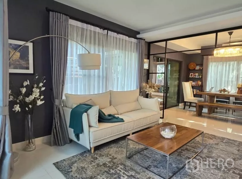 Detached House for rent in Bang Phli, Samut Prakan - Bright living room with cream sofa, floor lamp, sheer curtains and a wooden coffee table