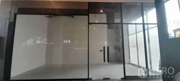 零售空间 出租 - 空置街铺，通高玻璃立面与双开玻璃门，白色墙面与水泥地面，可即刻装修，位于曼谷萨通区。