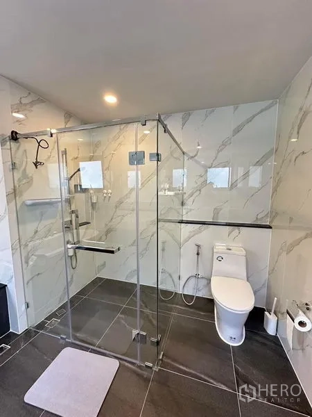 Detached House for rent in Bang Phli, Samut Prakan - Modern bathroom with marble-look tiles, glass-enclosed shower and toilet.