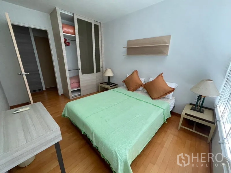 Condominium for sale in Khlong Toei, Bangkok - Second bedroom with built-in wardrobe and bedside tables.