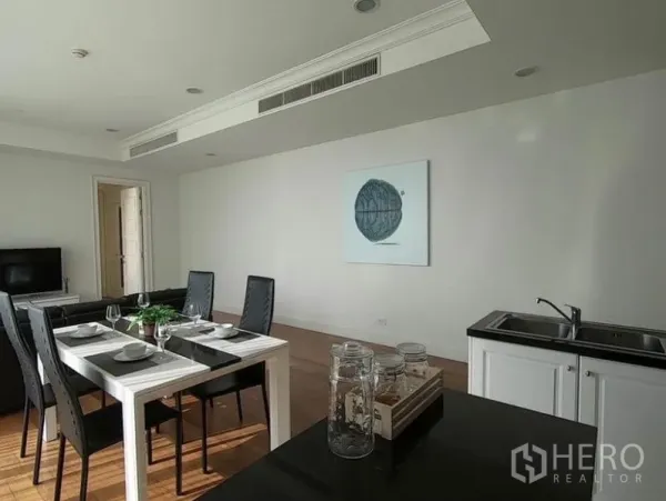 Condominium for rent in Watthana, Bangkok - Four-seat dining area beside a minimalist white pantry and TV in a light-filled room.