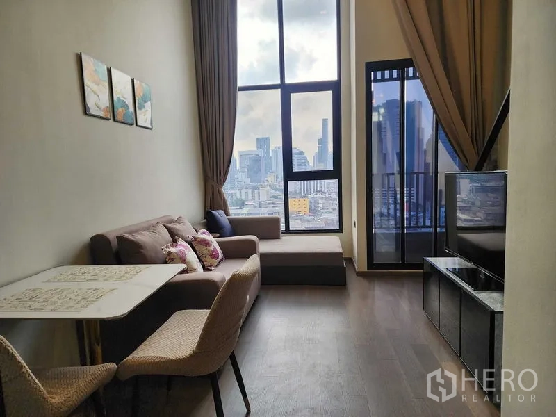 Condominium for rent - Living area with double-height windows, city skyline views, sofa and dining table.