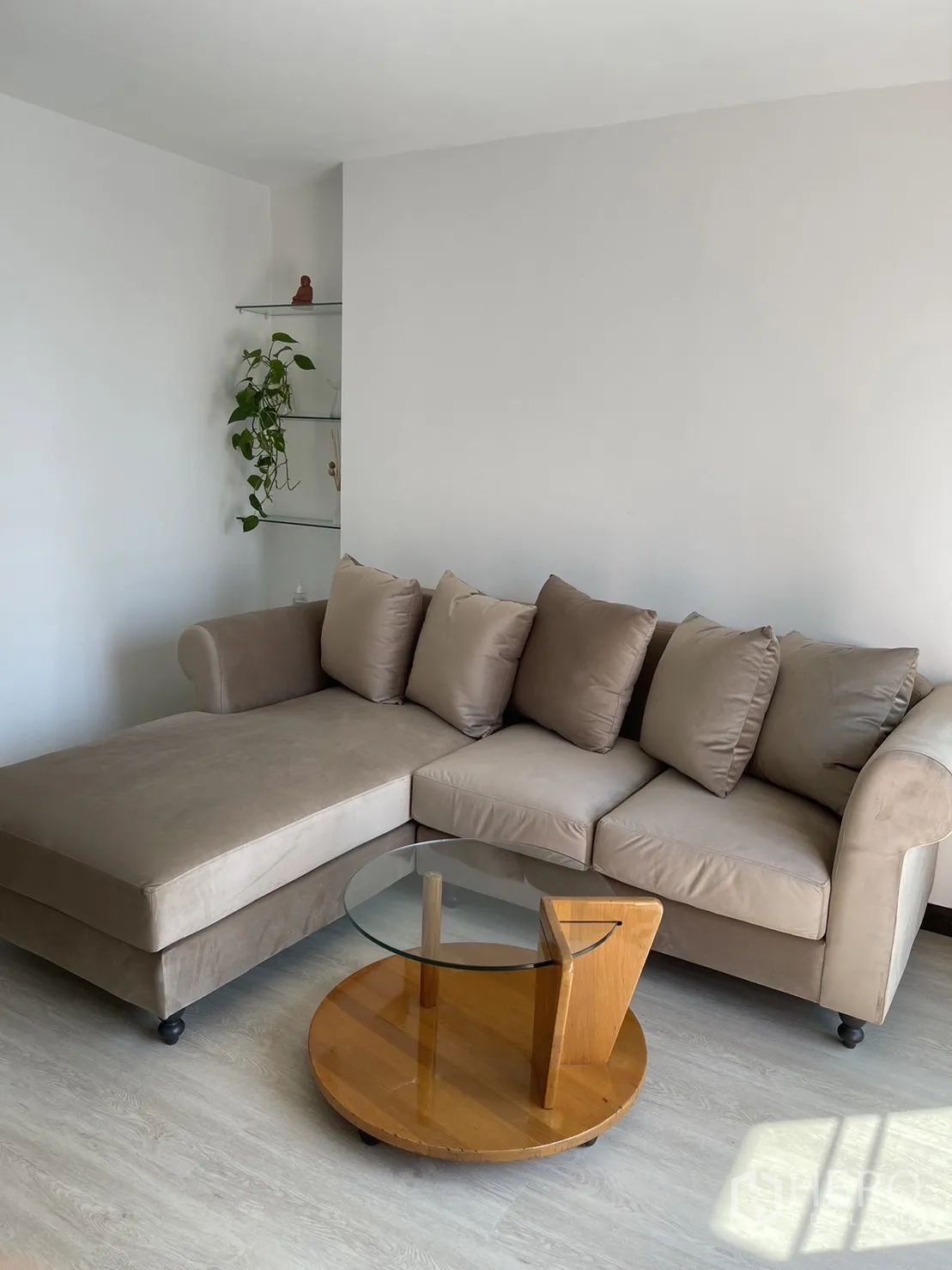 Condominium for rent or sale in Watthana, Bangkok - Living room corner with an L-shaped sofa and round glass coffee table.