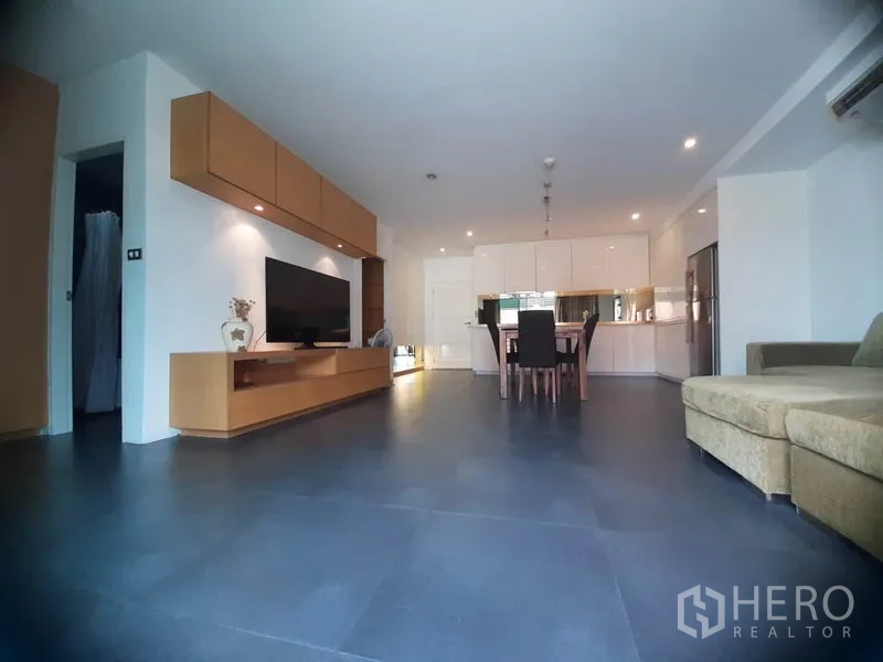 Condominium for rent in Phaya Thai, Bangkok - Spacious open living–dining room with sofa, TV console and dark tiled floors.
