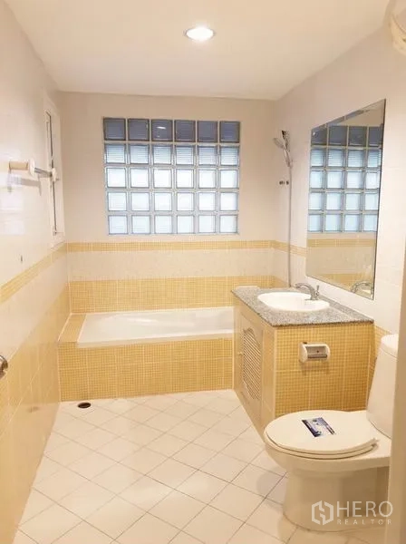 Townhouse for rent or sale in Chatuchak, Bangkok - Bathroom with yellow accent tiles, bathtub, vanity with granite countertop and large mirror.