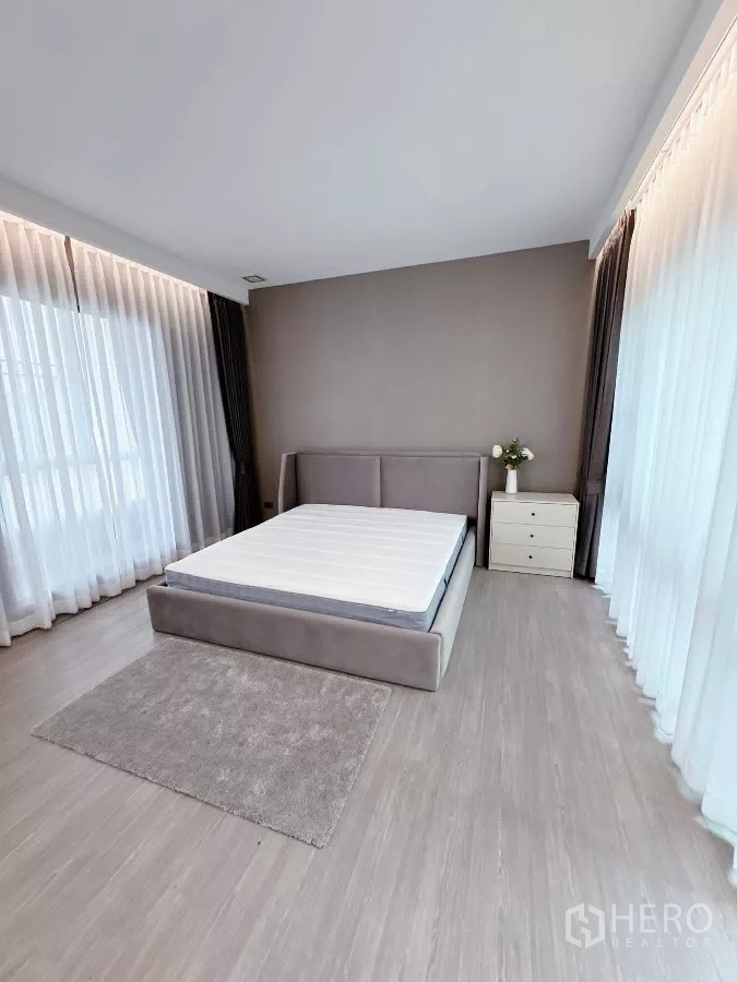 Townhouse for rent or sale in Lat Phrao, Bangkok - Master bedroom angle showing floor-to-ceiling sheer drapes.