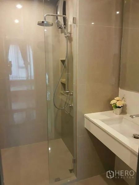 Condominium for rent in Khlong Toei, Bangkok - Contemporary bathroom featuring glass-enclosed shower and clean vanity.