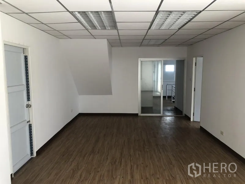 Factory for rent or sale in Bang Lamung, Chon Buri - Bright office room with sliding glass door, laminated floor and multiple ceiling lights.