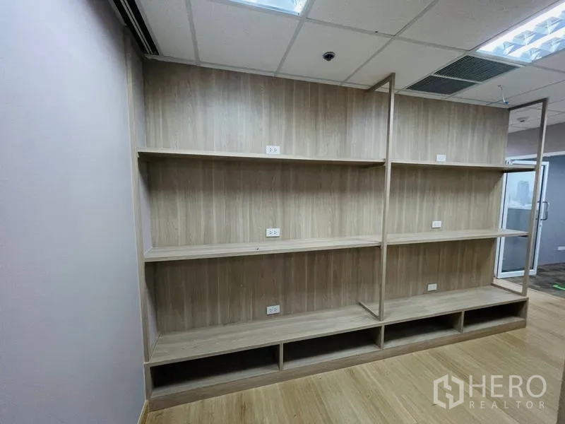 Office Space for rent - Built-in wooden shelving with power outlets along the wall.